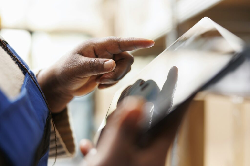 African american warehouse worker hand tapping on tablet screen