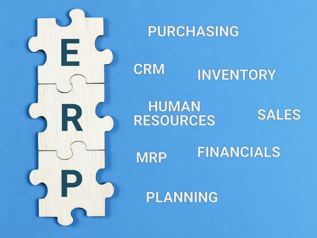 Enterprise Resource Planning concept. Text ERP with jigsaw puzzle pieces on blue background.