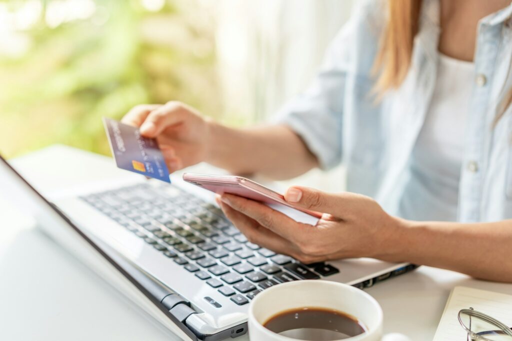 Young woman holding a credit card and using smartphone for making online payment shopping